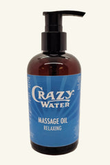 A bottle of Crazy Water Massage Oil with a pump dispenser, labeled 'Relaxing'. The bottle is brown with a blue label and black cap.
